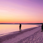 **Prompt:** A vibrant sunset at Sunset Point, Sweden. The sky is filled with orange, pink, and purple hues, reflecting on the calm, crystal-clear water. Soft white sand in the foreground leads to the sea. People are silhouetted, enjoying the view. Coastal setting, Scandinavian vibe.